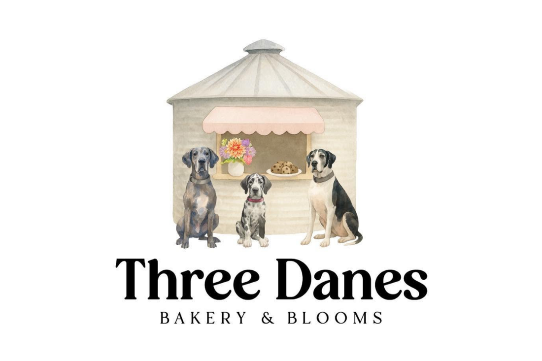 Drawing of a grain silo with three Great Dane dogs sitting in front of it with, underneath, the words Three Danes BAKERY & BLOOMS