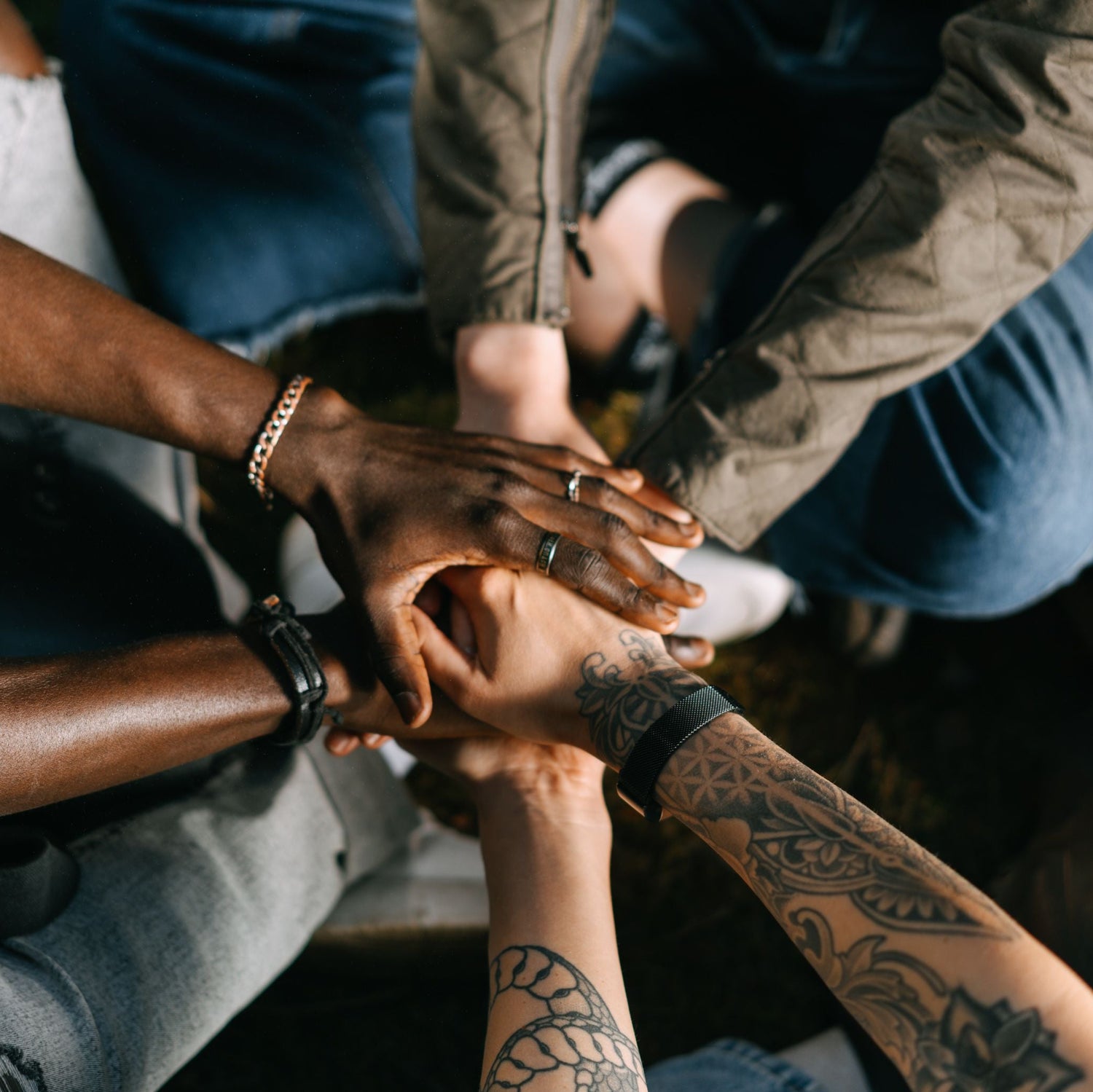 Group of people with interlocked hands, symbolizing unity and teamwork.