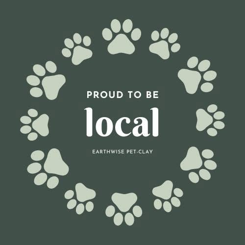 A square graphic with a dark green background, featuring a circular arrangement of light green paw prints around the words 'PROUD TO BE local' in white, with 'EARTHWISE PET-CLAY' underneath.