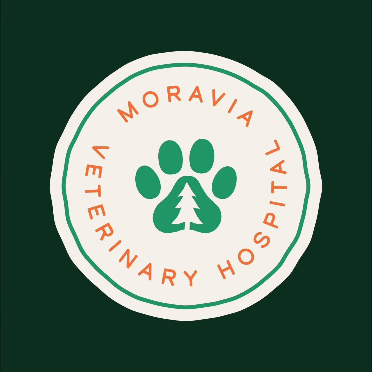 A circular white sticker or label with a green paw print and tree emblem in the center, surrounded by the words 'MORAVIA VETERINARY HOSPITAL' in orange text, shown on a dark green background.