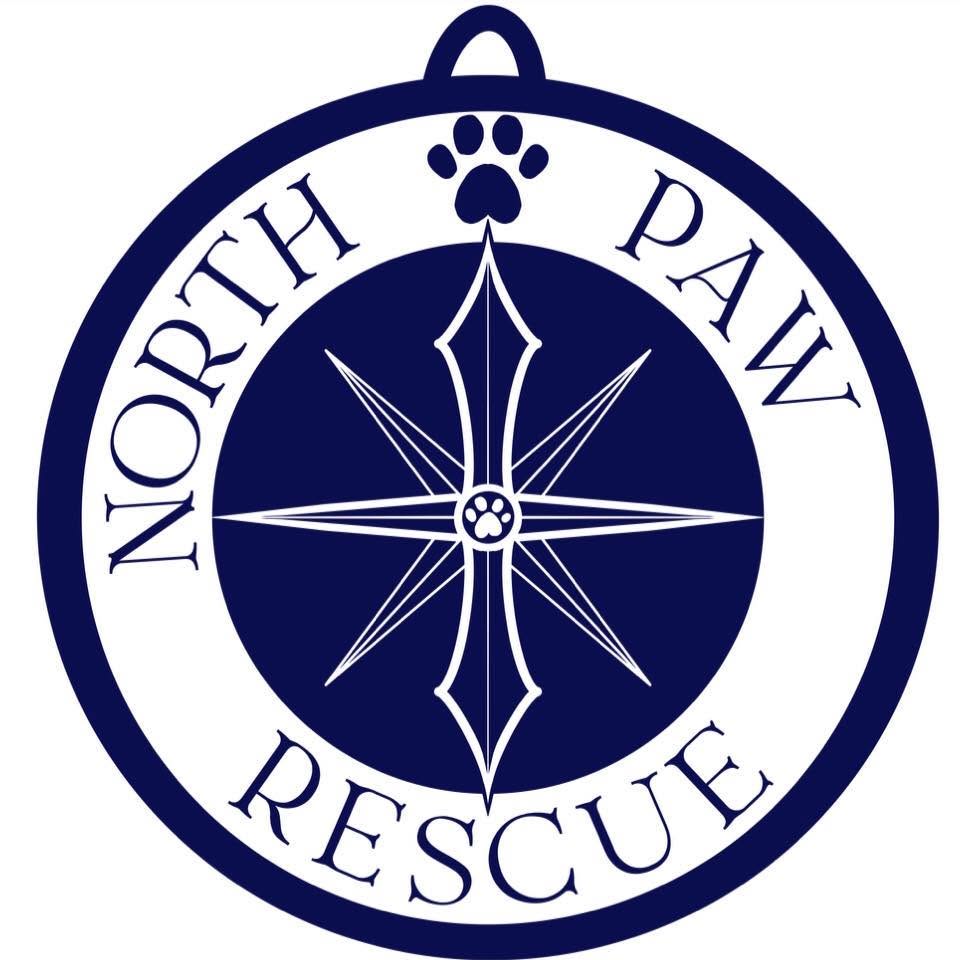 A circular North Paw Rescue emblem or sign with a white border, navy blue center, compass rose, paw print, and the words NORTH PAW RESCUE on a white background.
