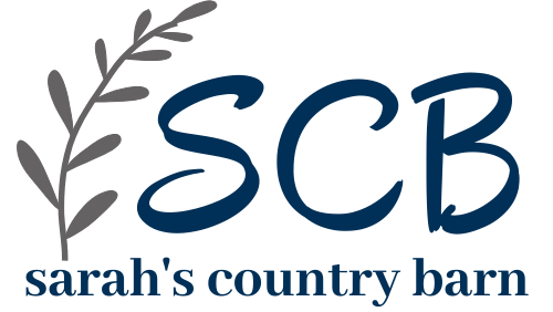 A logo featuring the letters 'SCB' in dark blue script with a gray leafy branch on the left, and the words 'sarah's country barn' in dark blue below, on a plain white background.