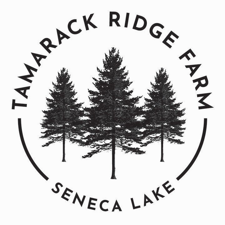 A circular black-and-white logo featuring three pine trees in the center, with the words 'TAMARACK RIDGE FARM' arched above and 'SENECA LAKE' curved below on a white background.